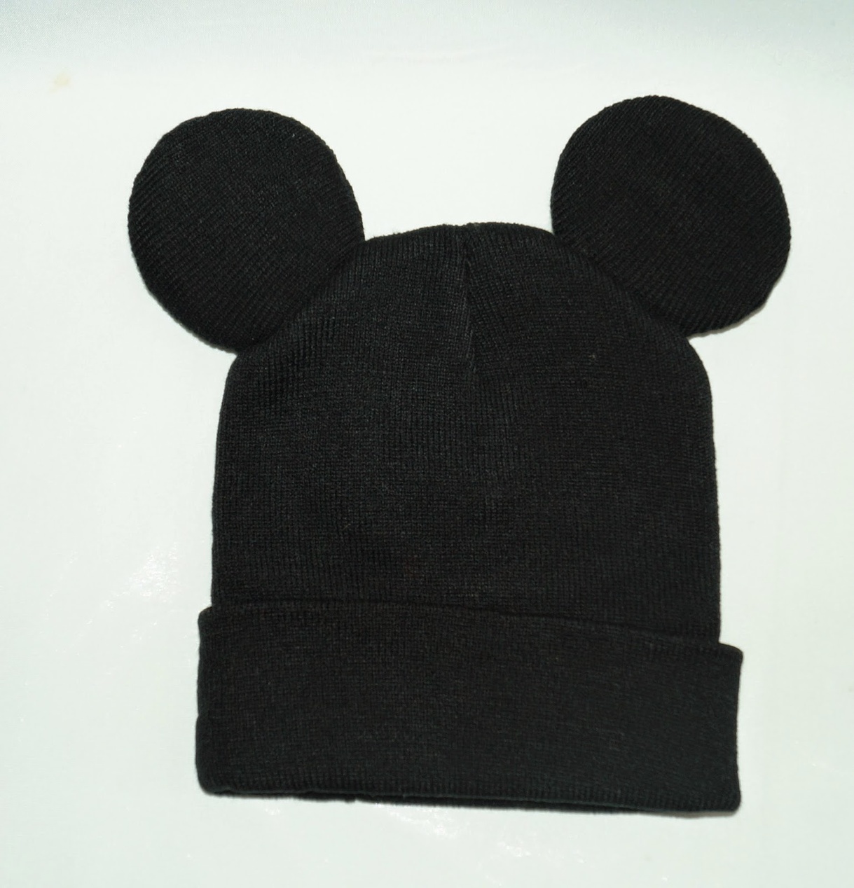 Eine schwarze Strickmütze mit aufgenähten Micky Maus Ohren aus geripptem Stoff, eine wintertaugliche Modeinterpretation der ikonischen Ohrensilhouette.
