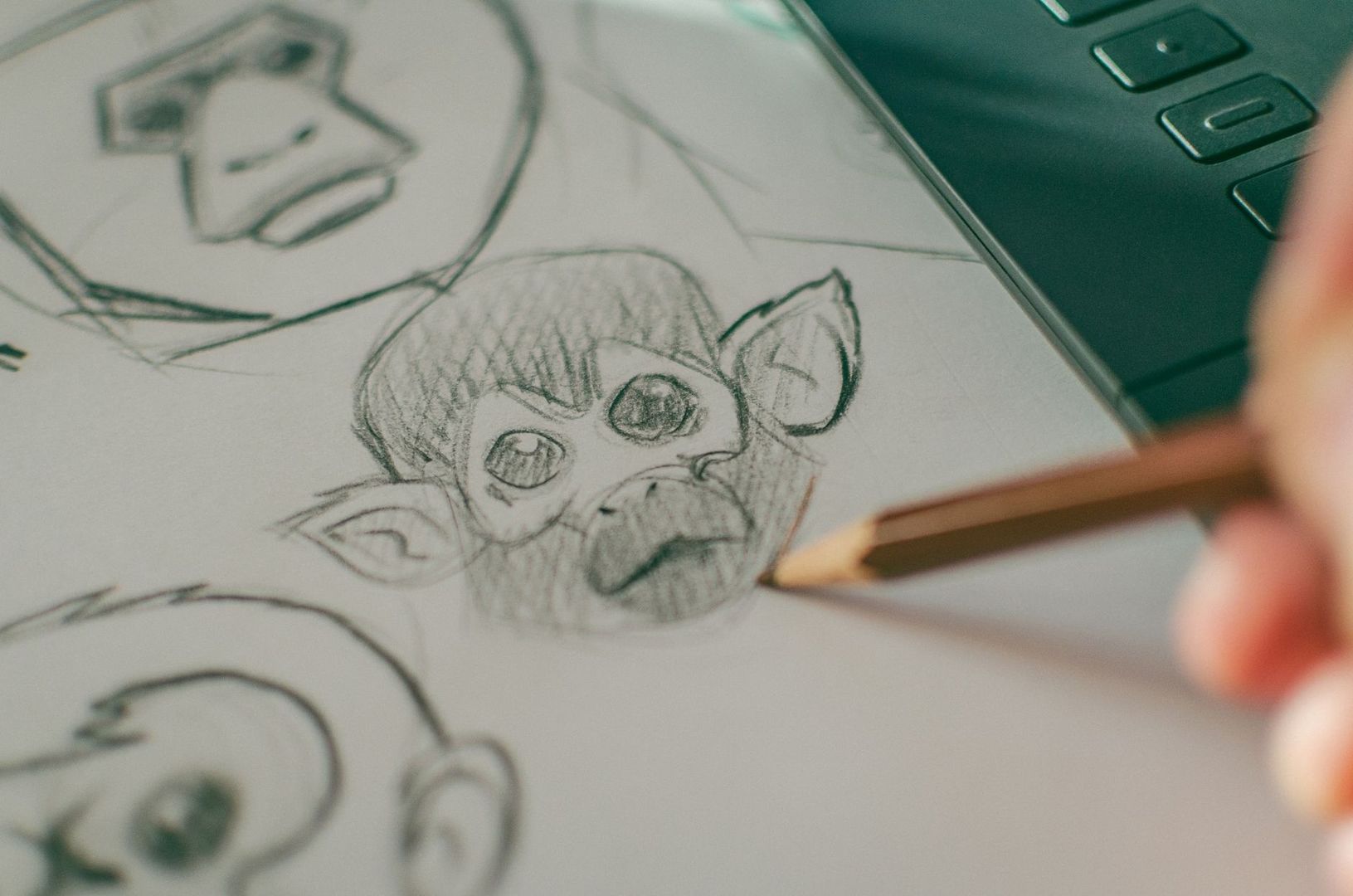 Bleistiftskizze einer Trickfilmfigur neben einem Zeichenstift und Grafiktablett